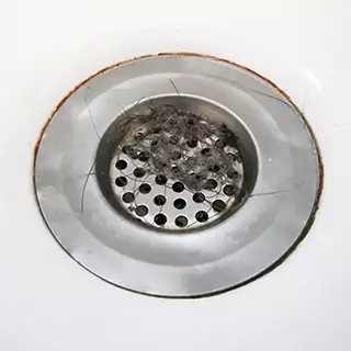 Ein Sieb im Abfluss der Dusche fängt Haare auf und beugt somit einer Verstopgung vor. Abfluss mit Sieb